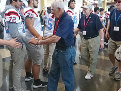 veterans shake the hands of football players